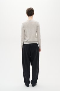 Light gray fitted sweater paired with loose black trousers, seen from behind. Sweater has a round neck; trousers have a relaxed fit.
