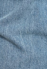 Tissu en denim bleu clair avec un motif de tissage diagonal subtil, affichant une texture douce et un ton de couleur uniforme.