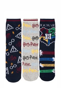 Tre paia di calzini a tema Harry Potter: blu scuro con occhiali e simboli, grigio con testo "Harry Potter" e lo stemma di Hogwarts.