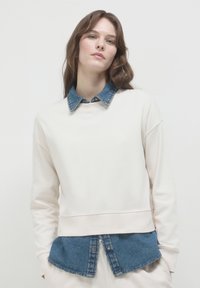 Felpa beige chiaro con colletto e orlo in denim. Tessuto misto cotone, vestibilità comoda, cuciture visibili e look a strati.
