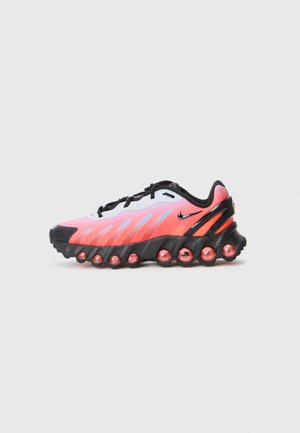 Nike running shoe with a white, pink, and black design, featuring a mesh upper, thick black sole, and distinct round cushioning details.
