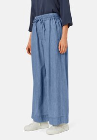 Pantalones de pierna ancha en azul claro, con cintura elástica y cordón ajustable. Elaborados en tejido suave, presentan un corte recto y sutiles detalles de costura.