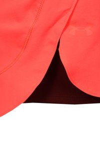 Korallfarbenes Sportoberteil mit abgerundetem Saum, sichtbaren Nähten und einem Under Armour-Logo in matter Optik an der Seite.