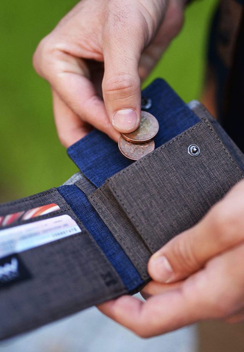 A brown fabric wallet with a blue interior; holding coins. Features card slots and a snap closure. Textured surface and compact design.