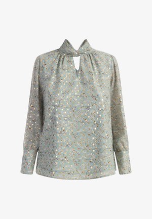 Lysblå bluse med blomster, der har en nøglehulshalshals, lange ærmer og en glat tekstur. Har detaljerede blomsterdesigns i pastelfarver.