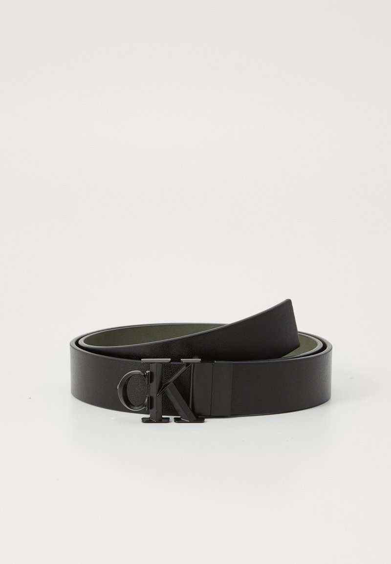 Zwarte leren riem met een glanzende afwerking, voorzien van een matte zwarte gesp met een CK-logo. De binnenkant is gevoerd met groen en laat een dubbel-laags ontwerp zien.