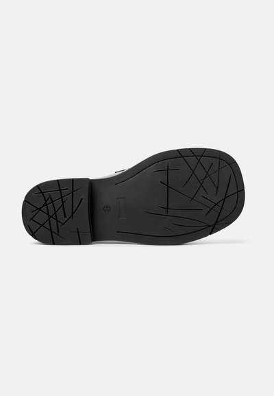 Semelle de chaussure en caoutchouc noir avec texture antidérapante, présentant un motif en zigzag et des rainures de flexion pour l'adhérence. Forme plate et arrondie.