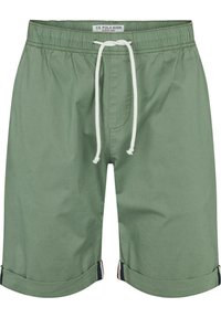 Zelené bavlněné šortky s elastickým pasem, šňůrkovým zavíráním a ohrnutými lemy. Obsahují přední kapsu a barevně kontrastní detaily.