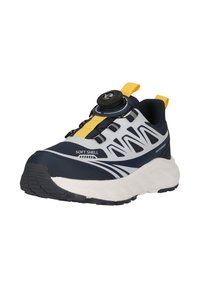 Baskets étanches bleu marine et blanches avec languettes de traction jaunes et système de fermeture à cadran, étiquetées "Soft Shell", dotées d'une semelle épaisse blanche et d'une semelle extérieure à relief.