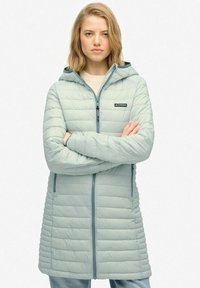 Lyseblå polstret jakke med hætte, med lodret quiltet design, frontlynlås og to sidelommer. Justerbar snor i hætten.
