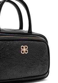 Zwarte leren handtas met een gestructureerd oppervlak, voorzien van een gouden rits en een gouden logo-accent aan de voorkant. Dubbele handgrepen aan de bovenkant.