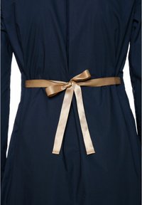 Tengerészkék ruha sima textúrával, arany szaténszalaggal megkötve a deréknál. A hátoldal tiszta kialakítású, díszítések nélkül.