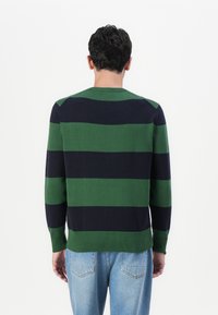 Pleten sweater s horizontalnim prugama u tamnozelenoj i mornarskoj plavoj boji. Okrugli izrez i rebrasti završeci rukava. Mekana, teksturirana tkanina.