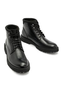 Czarne skórzane botki za kostkę z zaokrąglonym czubkiem, sznurowanym przodem i teksturowaną gumową podeszwą zapewniającą dobrą przyczepność. Posiadają metalowe oczka i wyściełany kołnierz.