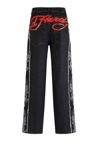 Black denim jeans featuring a wide-leg cut, red graphic text on the back, and intricate gray patterns along the side seams.