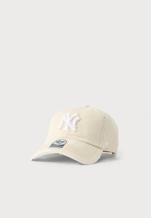 Cappellino da baseball beige con logo "NY" bianco ricamato, visiera curva e cinturino regolabile su sfondo grigio chiaro uniforme.