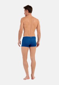 Shorts de bain bleus à motif géométrique avec une coupe ajustée, une taille contrastante et une finition élastique pour plus de confort.