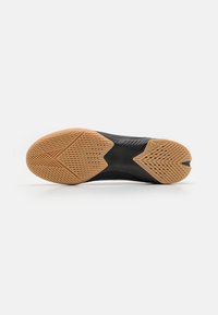 Suela de zapato atlético negro con una superficie de goma texturizada, que presenta un patrón de banda de rodadura en zigzag único y un diseño de tacón pronunciado.