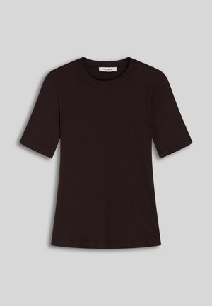 Haut noir ajusté à manches courtes, jean taille haute léger gris à jambes larges, et escarpins noirs à bout pointu, tenant une pochette texturée blanche.