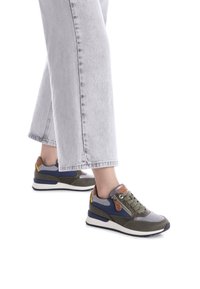 Zapatillas en verde oliva, gris y azul marino con tela texturizada y acentos lisos. Cuentan con cordones y una cremallera lateral para estilo y comodidad.