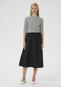 Falda midi negra con cinturilla elástica combinada con una blusa de rayas de manga corta que presenta un escote con forma de ondas. Textura de tela suave.