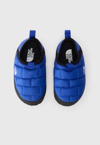 Kék párnázott slip-on cipők fekete részletekkel, steppelt mintával, lekerekített orral és texturált fekete gumitalppal. A márk logója látható belül.
