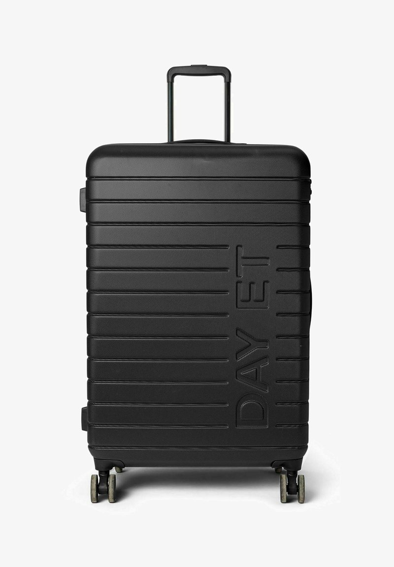 Valise rigide noire à surface texturée, dotée de rainures horizontales, d'une poignée télescopique et de quatre roues pour la mobilité.