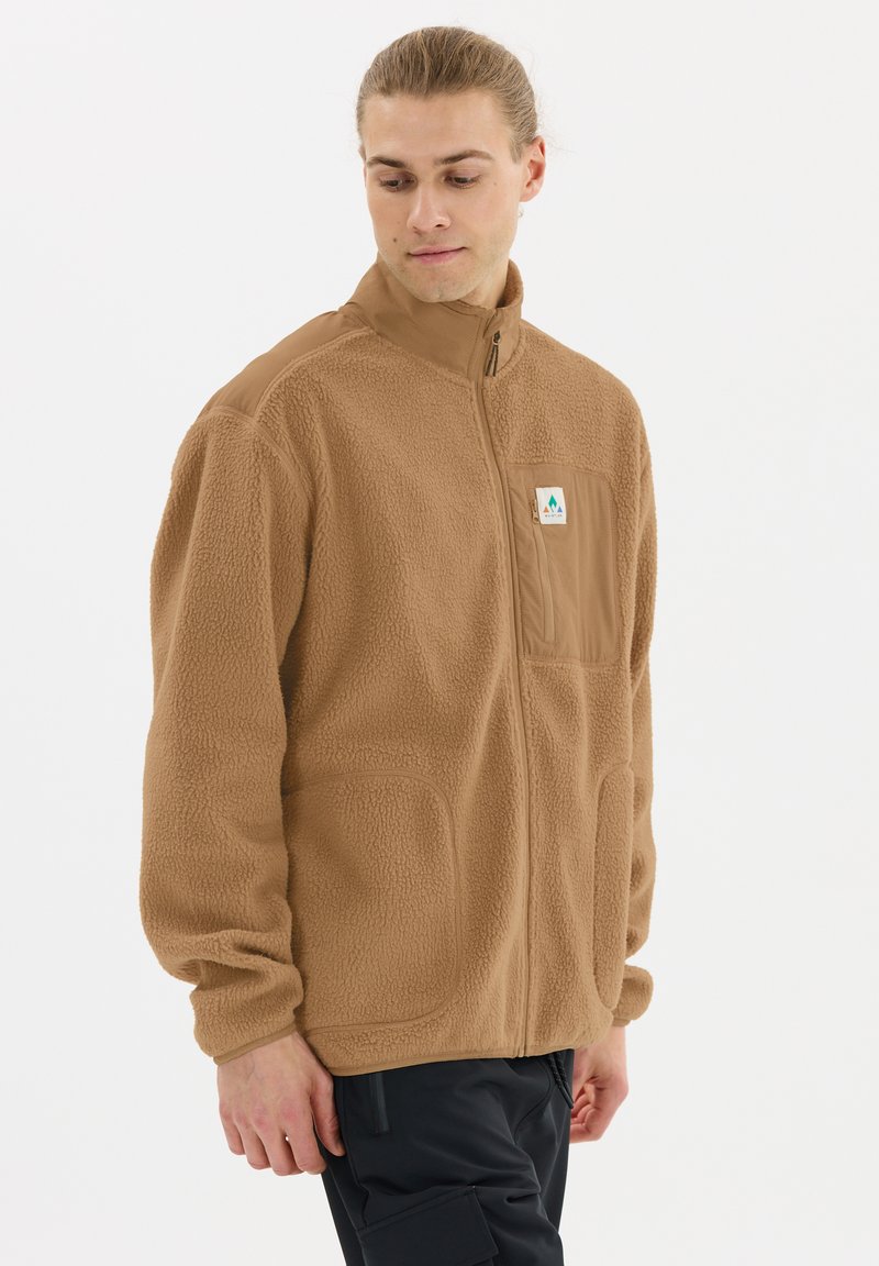 Veste en polaire marron avec un col haut, fermeture éclair et deux poches avant. Présente un petit patch logo sur la zone de la poitrine.