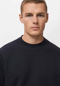 Zwarte crewneck sweatshirt gemaakt van gladde stof met een zachte textuur. Kenmerkt zich door subtiele stikdetails op de halslijn en schouders.