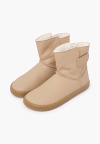 Beżowe skórzane botki za kostkę z podszyciem z sztucznego futra, płaską gumową podeszwą oraz paskiem na rzep dla regulowanego dopasowania. Gładka faktura.