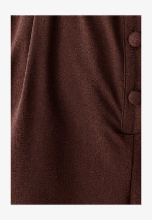 Bruine stof met een gestructureerde weving en een zachte uitstraling. Het kledingstuk heeft ronde knopen en een geplooid ontwerp.