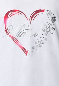 Biała koszulka z nadrukiem serca w kolorze czerwonym i srebrnym oraz tekstem "It’s Winter Time" i srebrnymi płatkami śniegu wokół grafiki.