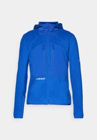 Jachetă fleece albastră cu un panou superior texturat și un panou inferior Neted. Include un fermoar frontal și două buzunare cu fermoar pe piept.