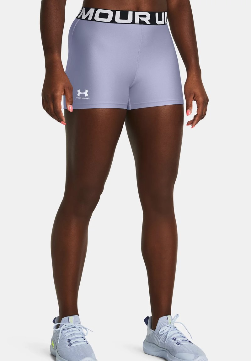 Helle lila Sportshorts mit einem breiten schwarzen Bund, auf dem "UNDER ARMOUR" steht. Schlanker Schnitt, glatter Textur und minimale Markenkennzeichnung.
