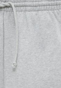 Lichtgrijze joggingbroek met een elastische tailleband en trekkoord. Zachte textuur met een geborstelde afwerking en een subtiel gespikkeld patroon.