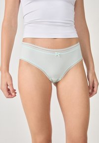 Mutande da donna verde menta chiaro in materiale a coste, con pizzo lungo l'elastico in vita e un piccolo fiocco decorativo sul davanti.