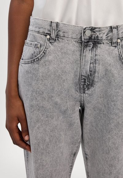 Vaqueros de mezclilla gris con un diseño clásico de cinco bolsillos, cierre de botón y una textura deslavada. La tela es suave y presenta una ligera variación de color.