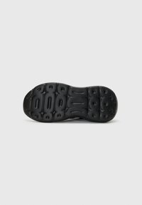 Semelle de sneaker noire en caoutchouc texturé pour l'adhérence, présentant de grands motifs en relief et une forme courbée pour le confort et le soutien.