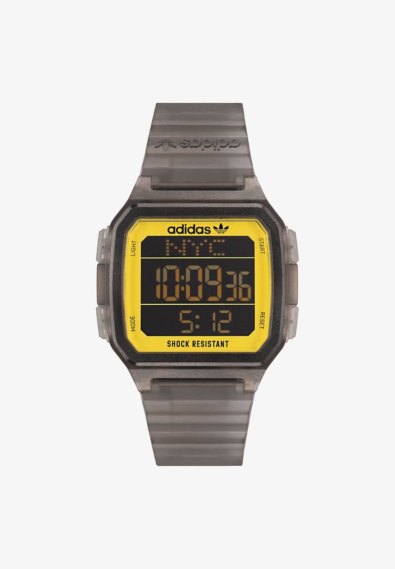 Skaitmeninis laikrodis su pilkai permatomu dirželiu ir stačiakampiu geltonu bei juodu ciferblatu. Ypatybės apima smūgiams atsparų korpusą ir kelis mygtukus.