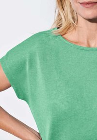 Groene T-shirt met korte mouwen, gemaakt van zachte stof, met een ronde halslijn en een ontspannen pasvorm, voorzien van een gladde, licht getextureerde oppervlakte.
