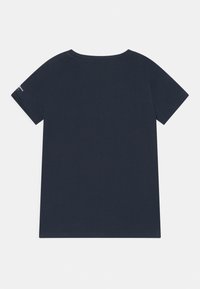 Námořnicky modré bavlněné tričko s krátkým rukávem, kulatým výstřihem a rovným lemem. Na levém rukávu je malý textový detail.