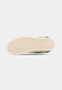 Shoe sole with a textured rubber surface; beige base and a light gray trim. Features a honeycomb pattern for traction.