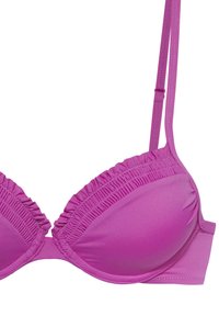 Roze bikini-top met gevoerde cups, gerimpelde rand langs de randen en verstelbare schouderbanden. Gladde textuur en naadloos ontwerp.