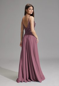 Robe longue et fluide en mauve avec un corsage en perles et un dos plongeant. Texture douce, plis accentuant la jupe. Bretelles fines réglables.