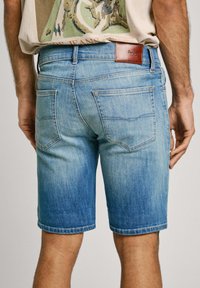 Gaišzilā denimpantu šorti ar izbalējušu apdari, piecu kabatu dizains un ādas uzlīme aizmugurējā jostasvietā. Kontrastējošās šuvju detaļas.