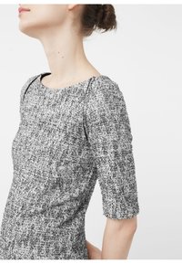 Harmaa ja valkoinen tekstuurinen mekko, jossa on pyöreä pääntie, kolmanneksen pituiset hihat ja mustat korost Stitching olkapäillä.