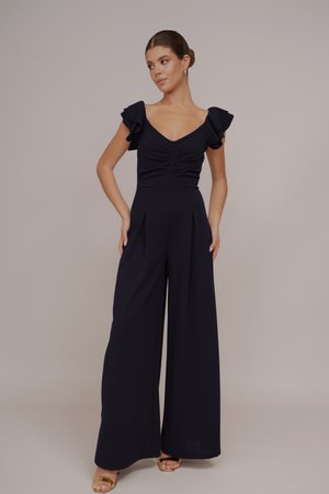 Mono marino con mangas cortas con volantes, escote en V, cuerpo ajustado y pantalones de pierna ancha con pliegues frontales. Textura de tejido suave.
