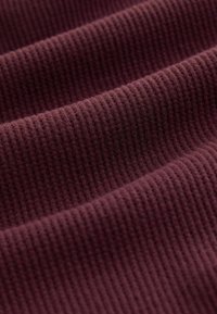 Burgundy ribbed fabric with fine, textured grooves. Soft and dense material, showcasing a rich color and uniform pattern across the surface.