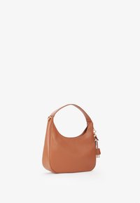 Bolso hobo de cuero marrón con forma redondeada, textura suave y un asa corta. Presenta un cierre de cremallera en tono dorado y un adorno de llavero desmontable.