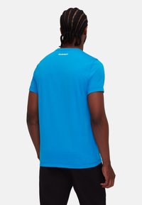 Blauwe T-shirt met korte mouwen van gladde stof. Heeft een ronde halslijn en het "Mammut"-logo op de achterkant, met een relaxte pasvorm.